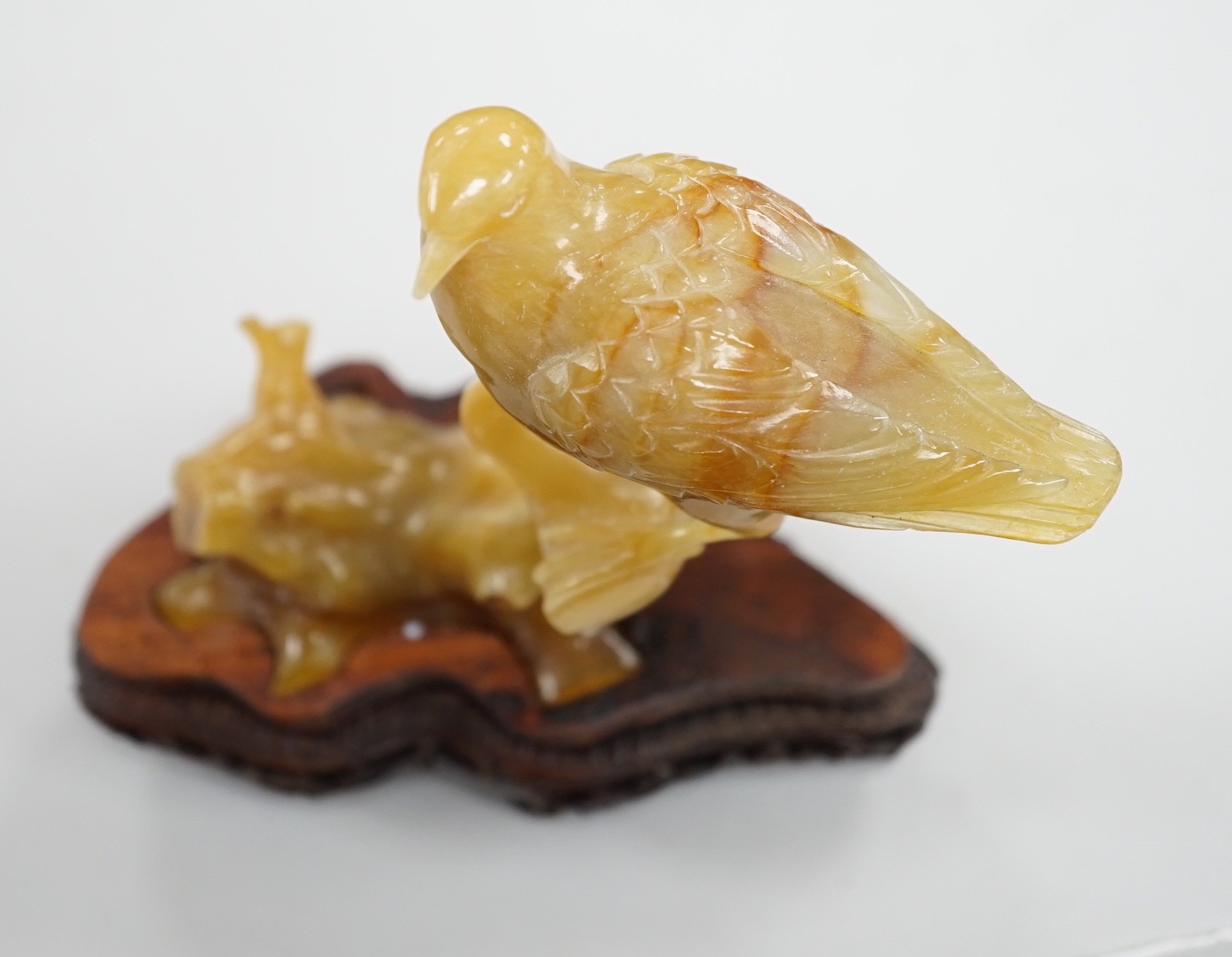 A Chinese chalcedony carving of a bird, wood stand, total height 15.5 cm